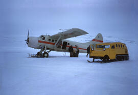 Beaver Aircraft landing on wheels in Isachsen. Early model of snowmobile by Bombardier